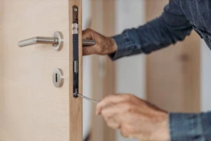 Locksmith repairing door lock with screwdriver for security and access. -locksmith services