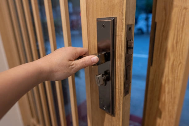 Hand turning door handle on modern wooden door with lock. -emergency locksmith services